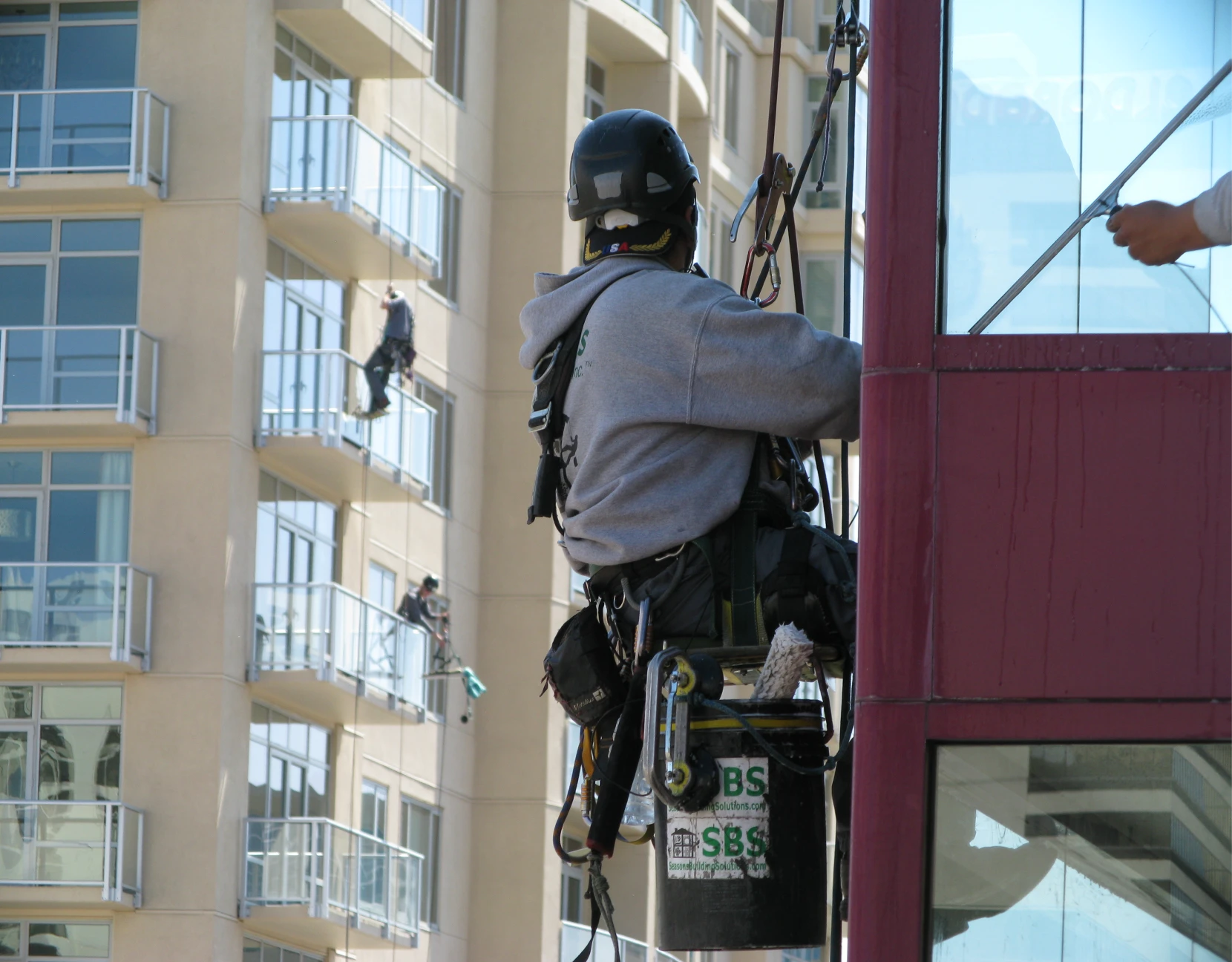 Worker suspended, cleaning high-rise building windows.