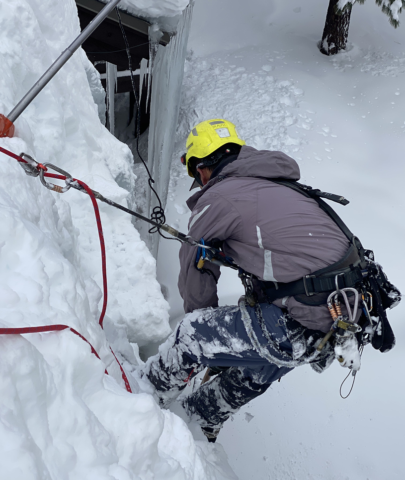 Climber ascending snowy slope with safety gear.